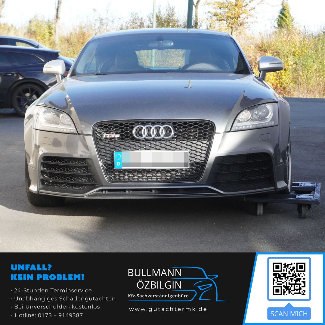 Frontansicht eines Audi TT RS mit markantem Kühlergrill und vier Ringen, geparkt auf einem Parkplatz.