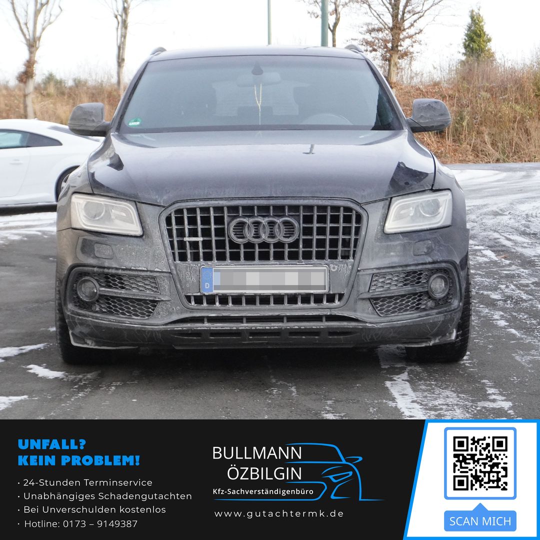 Vorderansicht eines schmutzigen Audi SUV auf einem Parkplatz mit Bäumen im Hintergrund.