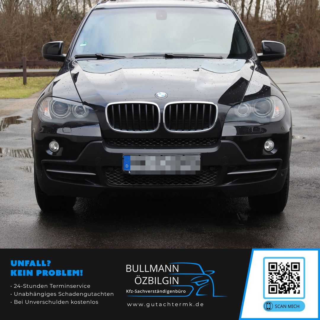 Schwarzer BMW SUV von vorne mit sichtbarem Kühlergrill und Scheinwerfern auf nasser Straße.