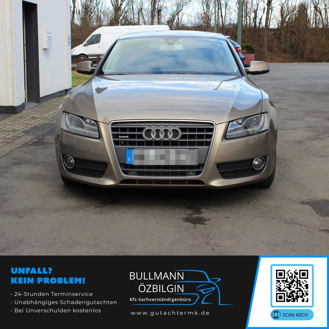 Vorderansicht eines geparkten Audi-Pkws vor einem Gebäude, im Hintergrund Bäume und ein weißer Transporter.