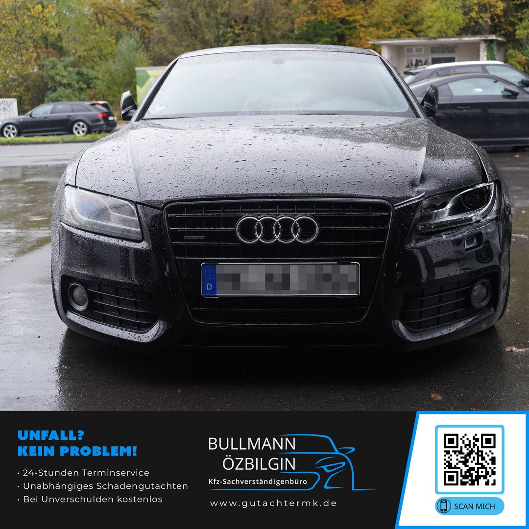 Schwarzes Audi-Auto von vorne mit nassen Regentropfen auf der Motorhaube, geparkt auf nassem Asphalt.