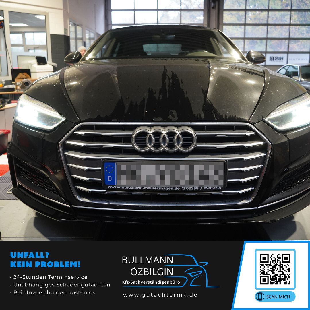 Schwarzer Audi mit beleuchteten Scheinwerfern in einer Werkstatt.