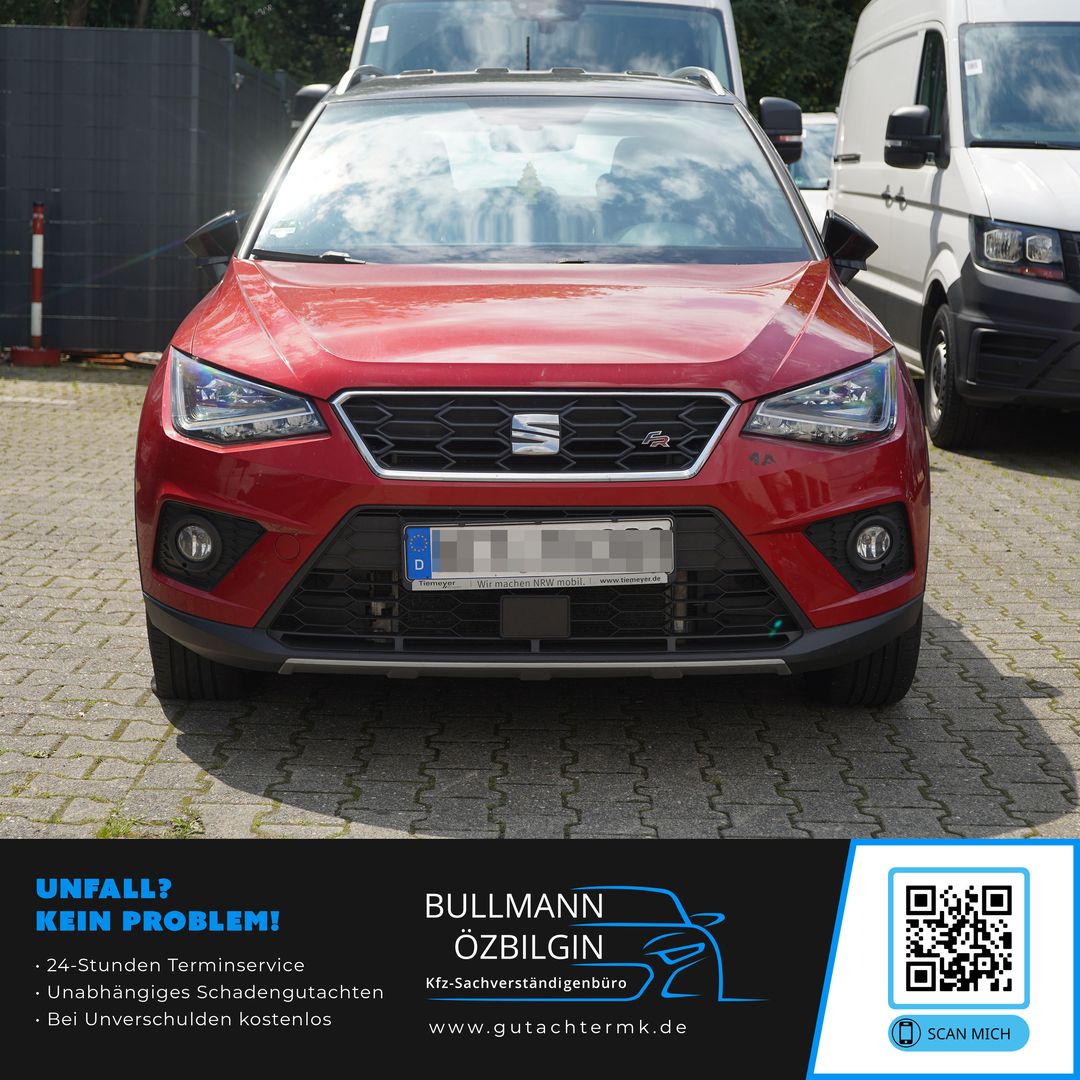 Roter Seat Arona SUV von vorne auf gepflastertem Parkplatz, mit zwei weißen Fahrzeugen im Hintergrund.