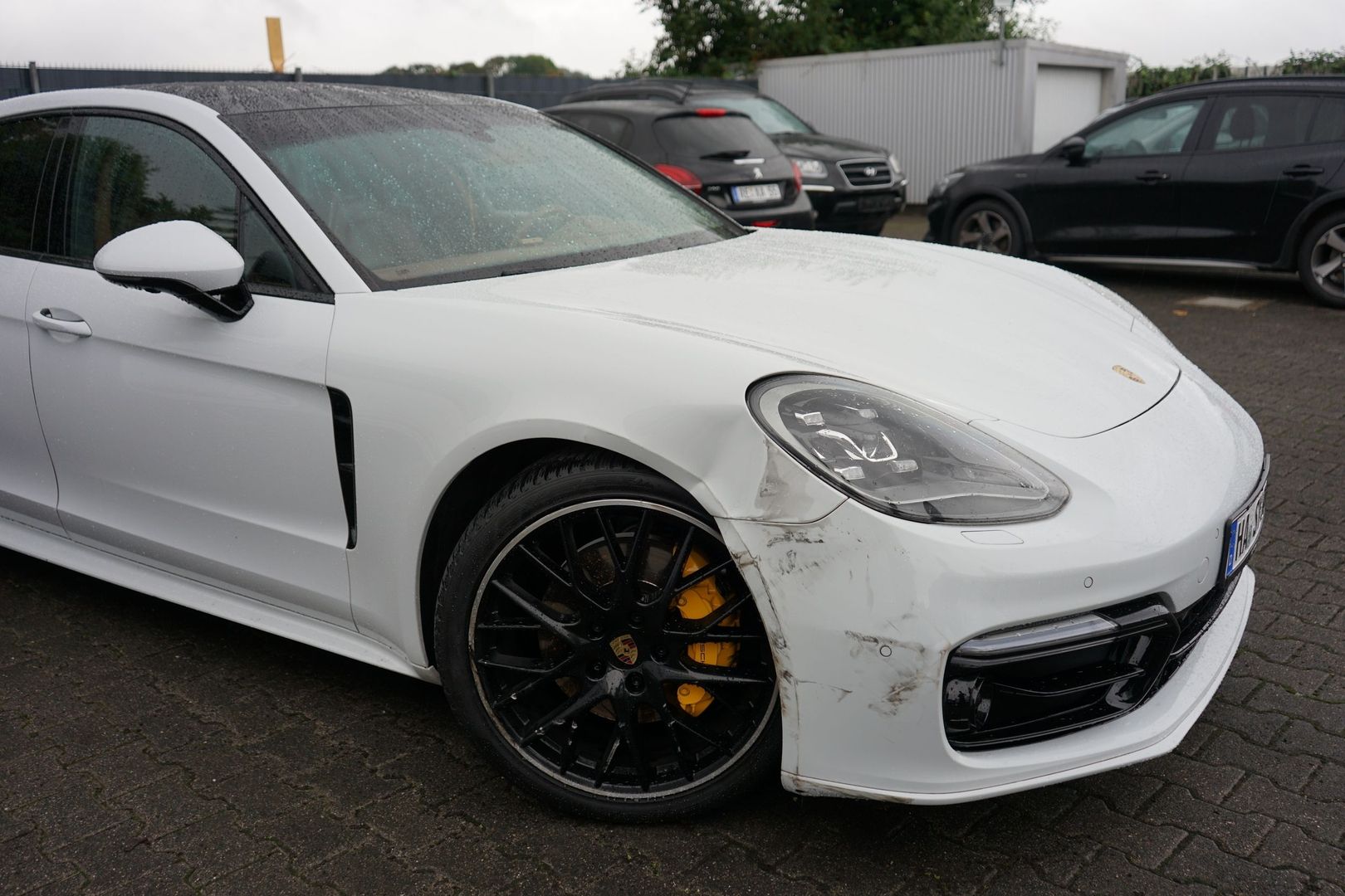 Seitenansicht eines weißen Porsche Panamera 971 4S mit deutlichem Streifschaden an der Frontschürze und dem Kotflügel vorne rechts