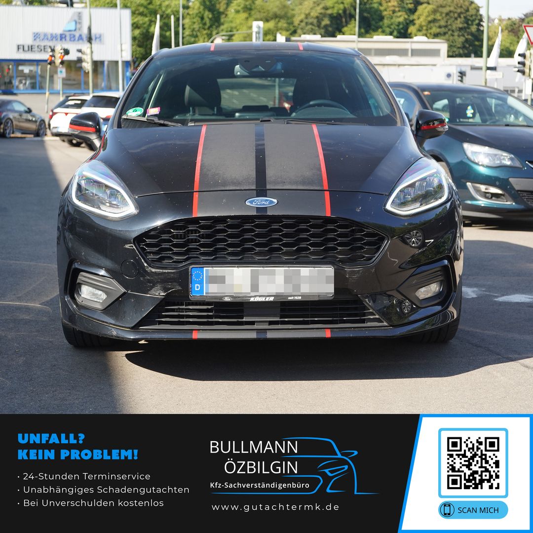 Schwarzer Ford Fiesta mit roten Rennstreifen, Frontansicht auf einer Straße mit weiteren Fahrzeugen im Hintergrund.