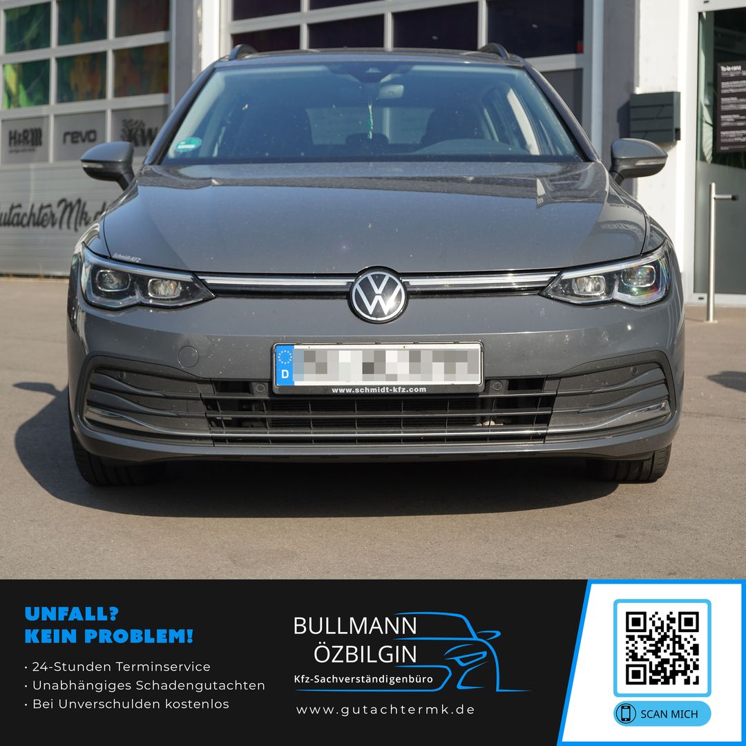 Frontansicht eines grauen Volkswagen Golf Variant mit sichtbarem Kühlergrill und Scheinwerfern, geparkt vor einem Gebäude.